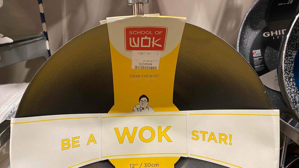 Nahaufnahme des grauen Wok-Materials mit Rillen eines Woks im Test der Marke Wok of School inklusive Preisetikett.
