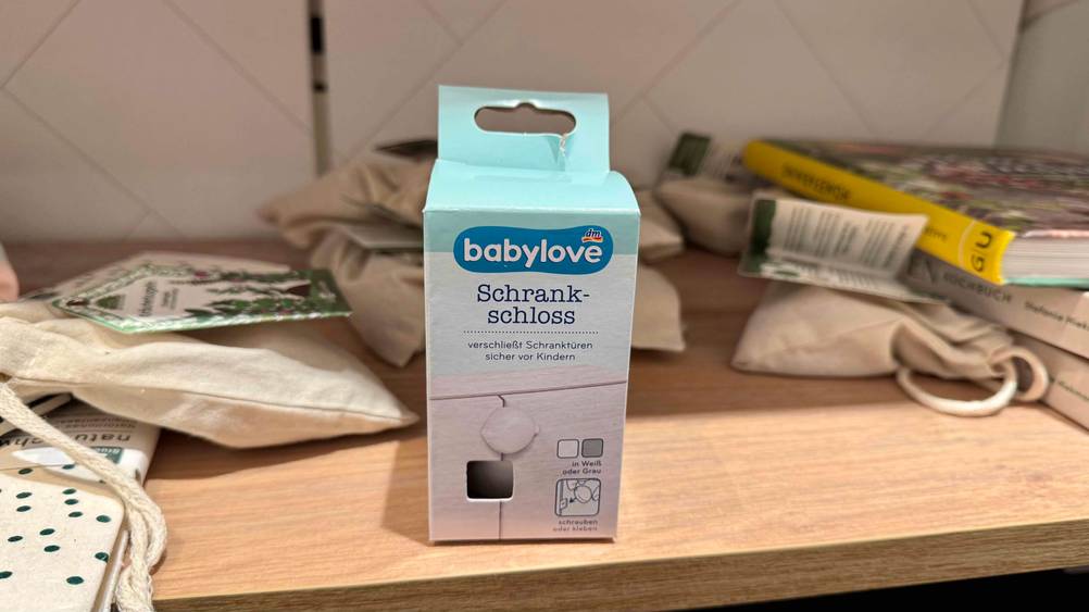 Ein verpacktes Schrankschloss im Test von vorne in einem Regal.