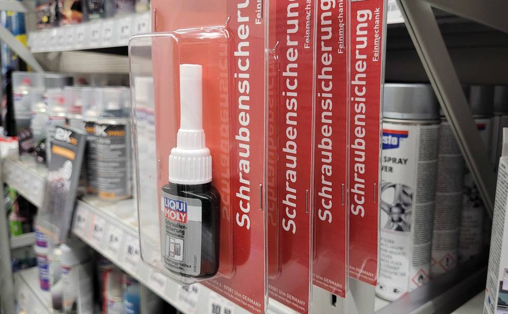 Schraubensicherung getestet: Mehrere Packungen der Schraubensicherung von der Seite an einem Regal hängend.