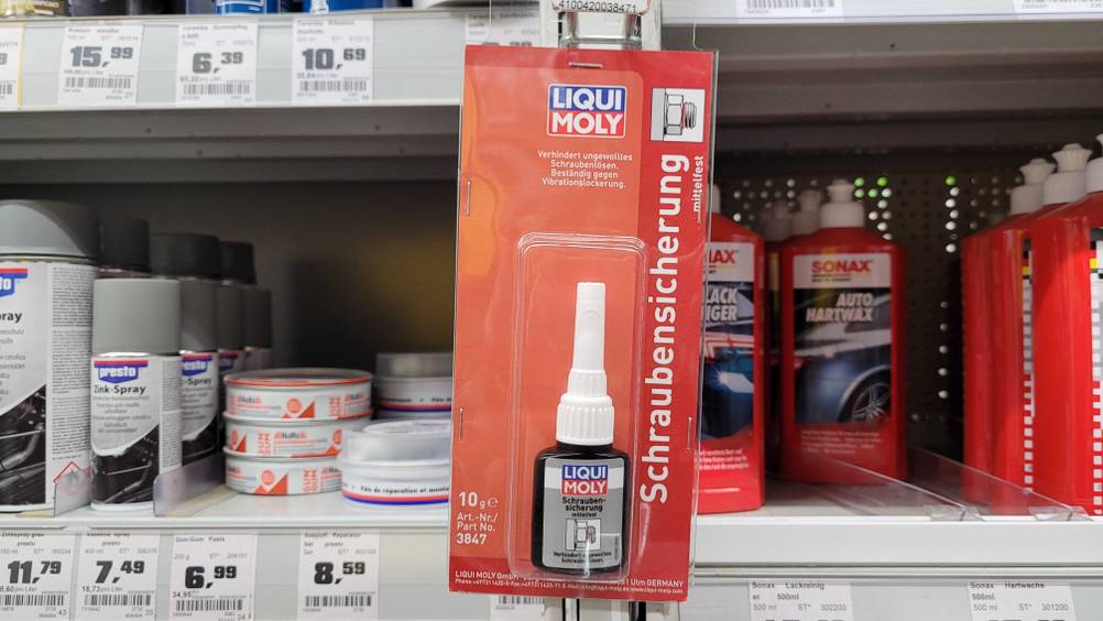 Eine originalverpackte Schraubensicherung im Test hängt an einem Verkaufsregal mit anderen Produkten.