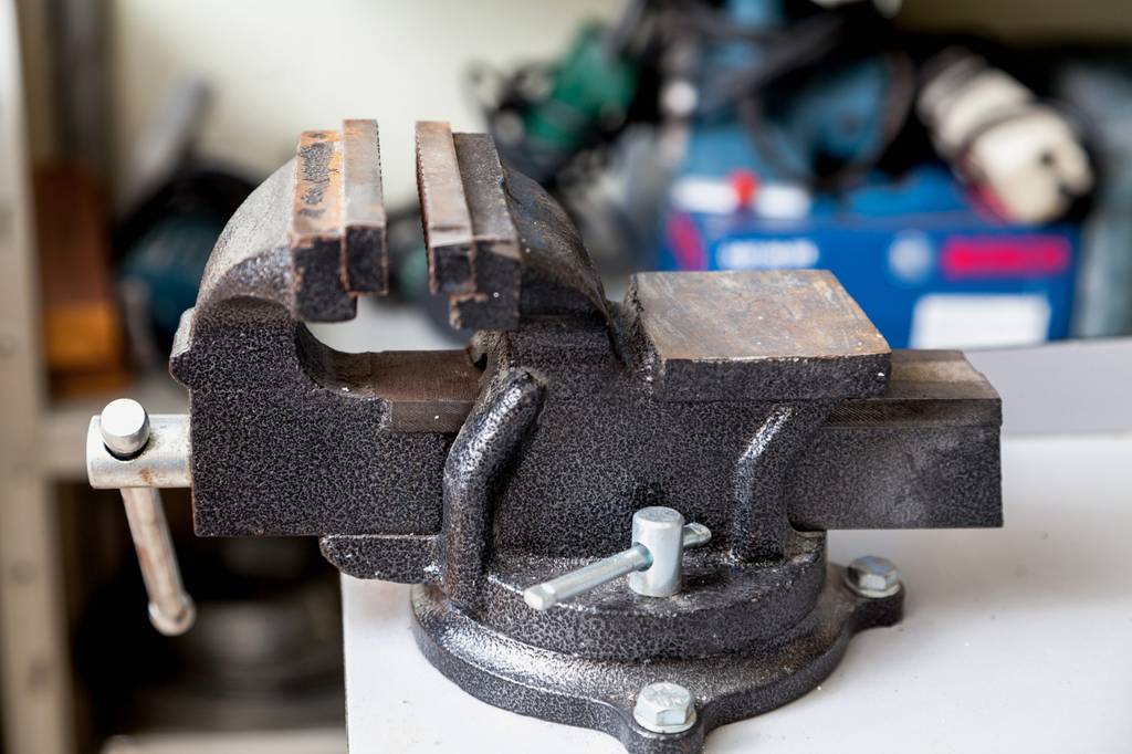 Schraubstock-drehbar-Test: Ein schwarz-hammerschlag-lackierter Schraubstock ist auf einer hellen Platte montiert und weist bereits Rostspuren auf.