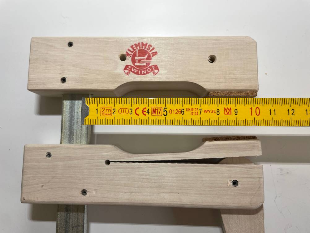 Schraubzwinge im Test mit Zollstock, der die Tiefe von 10 cm misst.
