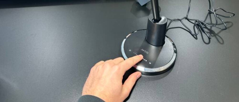 Eine Hand berührt das Touch-Bedienfeld der Jukstg-HD1906C-Schreibtischlampe, um die Helligkeit anzupassen.