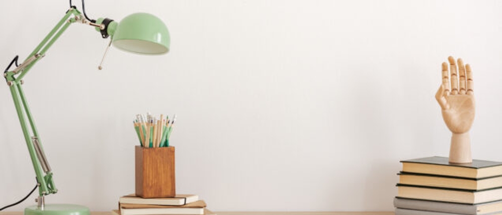 Grüne Schreibtischlampe auf einem Holzschreibtisch.