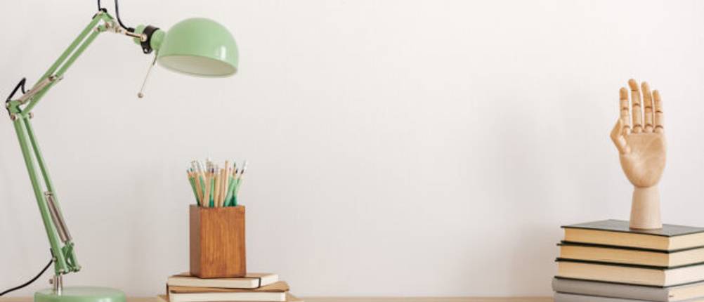 Grüne Schreibtischlampe auf einem Holzschreibtisch.