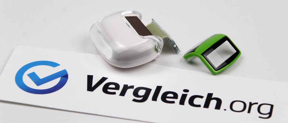 Schrittzähler im Test: Schrittzähler mit abgebrochenem Clip auf heller Unterlage samt Vergleich.org-Schriftzug
