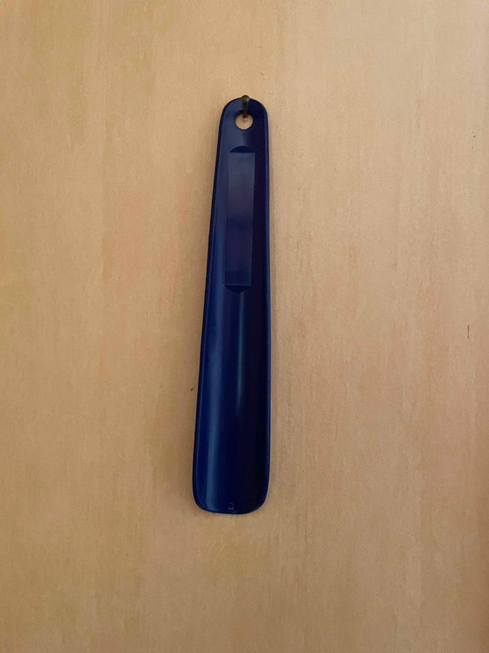 Ein Schuhlöffel im Test in blau hängt an einem Nagel.