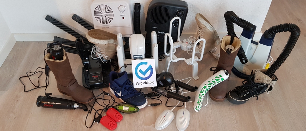 Viele verschiedene Schuhtrockner stehen zusammen mit Heizgeräten und Schuhen auf dem Boden