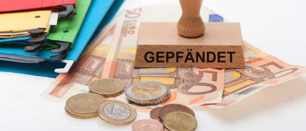 Schuldenanalyse-Test: Auf mehreren Geldscheine und Münzen steht ein Stempel mit der Aufschrift Gepfändet.