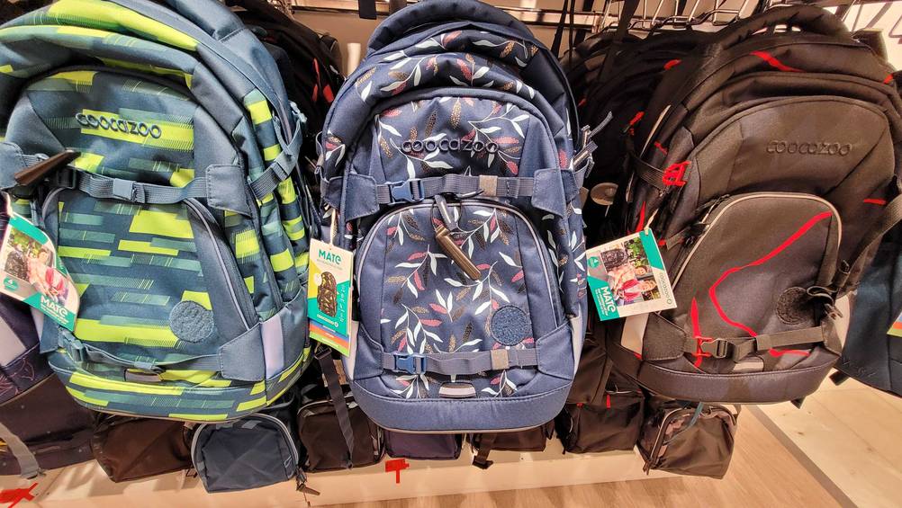 Ein getesteter Schulrucksack zwischen anderen in einem Regal hängend.