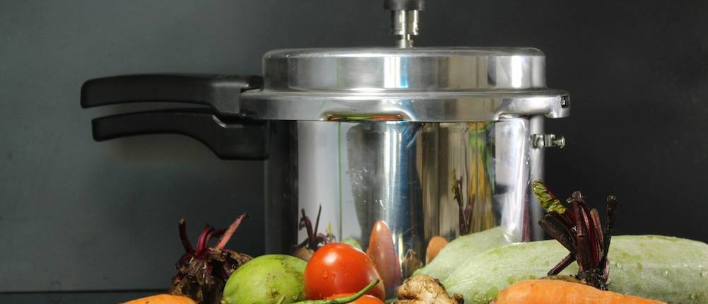 Schnellkochen im Test: Frisches Gemüse liegt vor einem Schnellkochtopf.