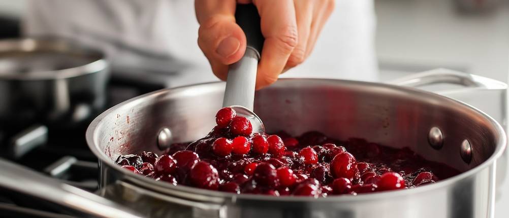 Der Saucen-Test im Stieltopf: Cranberries in einem Stieltopf, die mit einem Löffel umgerührt werden.