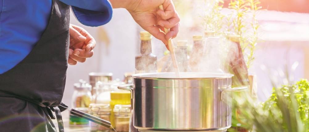 Im Koch-Test: Mann kocht in einem großen Suppentopf auf einem Gaskochfeld.