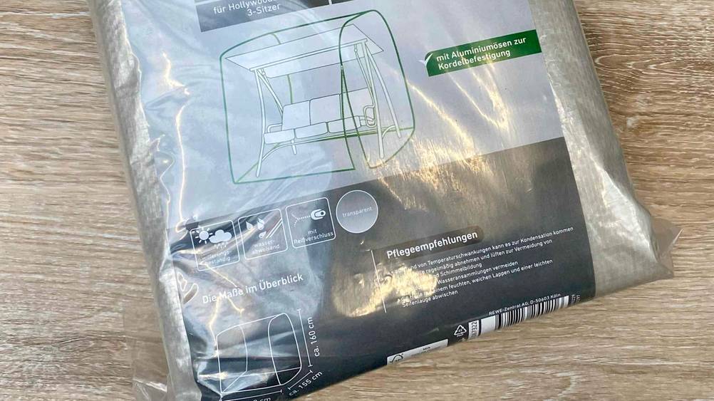 Nahaufnahme der Infografik auf einer Verpackung der getesteten Schutzhülle (Hollywoodschaukel) auf einer Holzfläche.