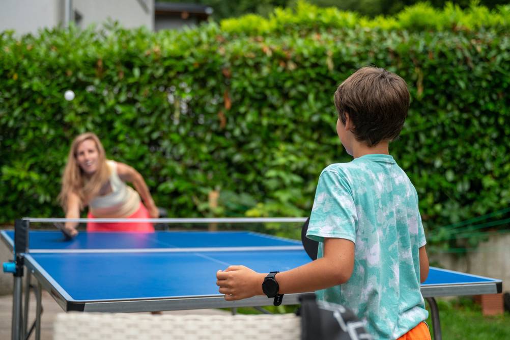 Schutzhuelle-Tischtennisplatte-Test: Eine Frau und ein Junge spielen Tischtennis im Garten.