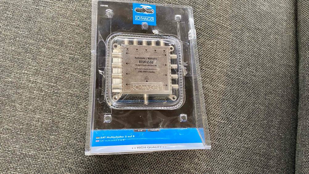 Ein transparent verpackter Multischalter im Test auf einem grauen Polster.