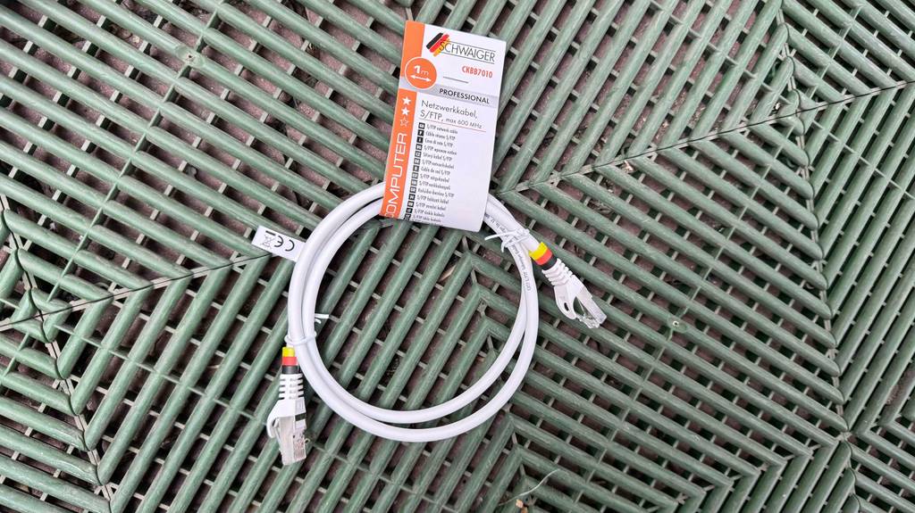 Ein getestetes Netzwerkkabel Cat 7 in Weiß liegt auf einer grünen Kunststoffplatte.