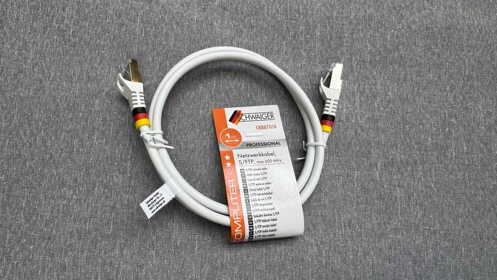 Getestet: Ein Netzwerkkabel Cat 7 in Weiß liegt auf einem grauen Stoffbezug.