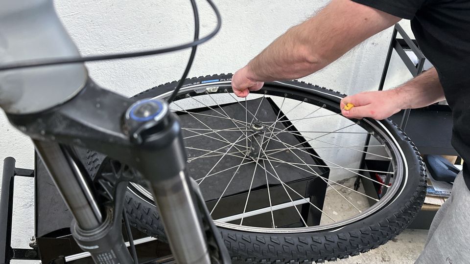 Ein Schwalbe Marathon Plus MTB HS468 Reifen wird vom Laufrad entfernt. Eine Hand löst die Reifenflanke vom Felgenhorn.