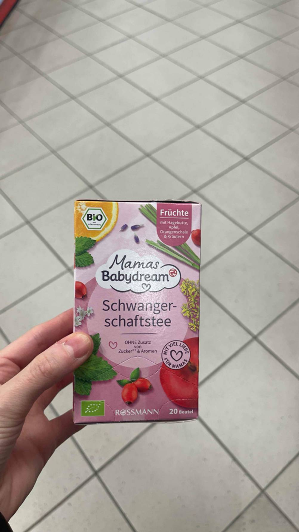 Eine Hand hält die Packung des getesteten Schwangerschaftstees hoch.