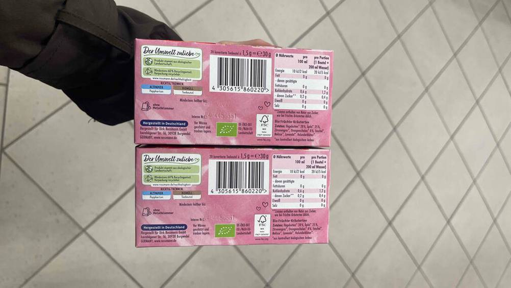 Schwangerschaftstee im Test: Eine Hand hält zwei Packungen mit der Rückseite nach vorne.