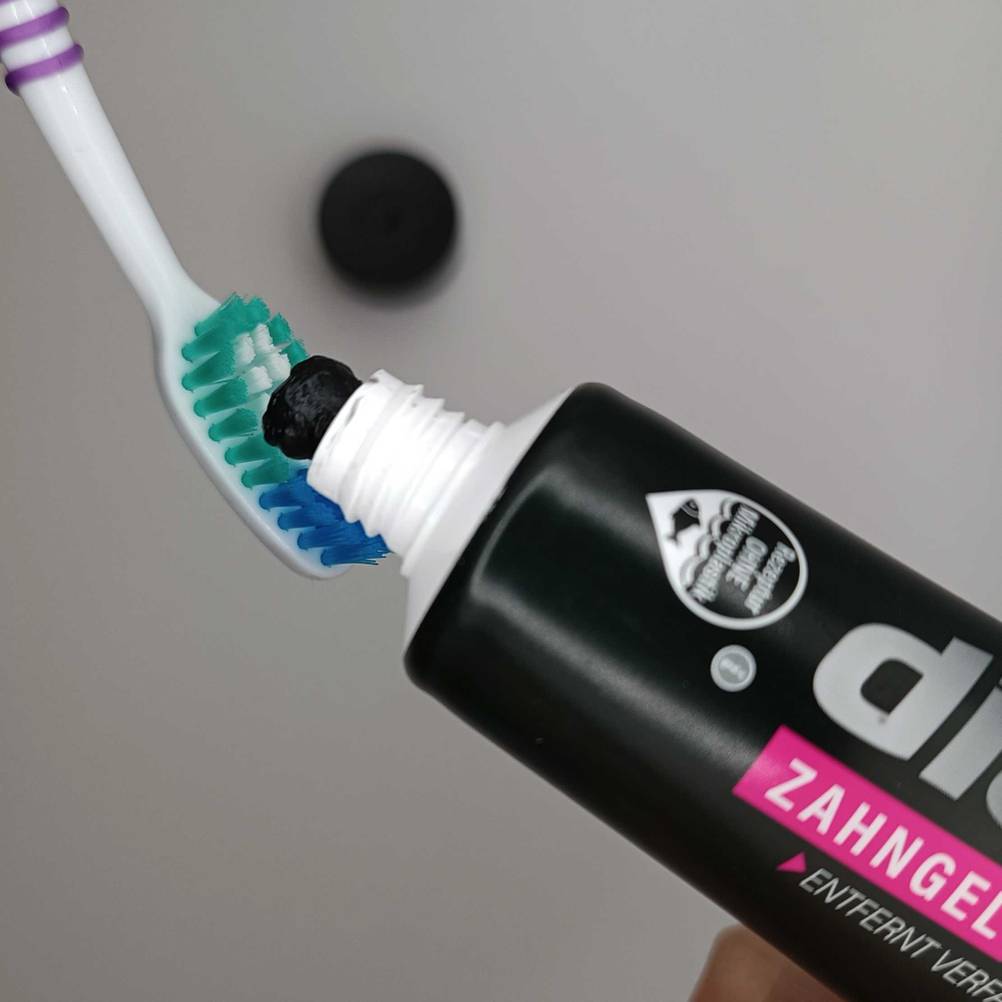 Schwarze Zahnpasta im Test: Zahnpasta wird auf eine Zahnbürste gedrückt.