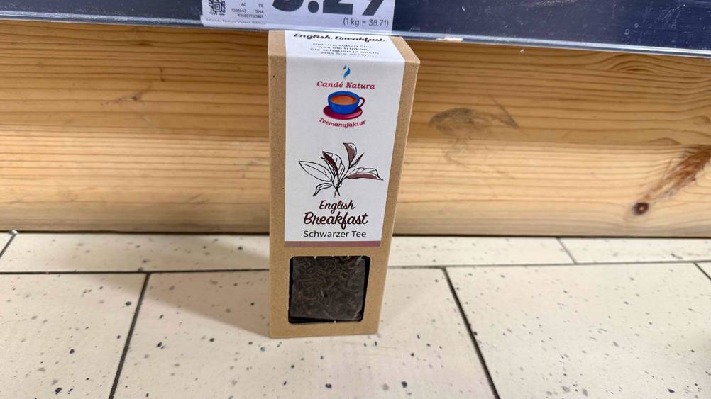Schwarzer Tee im Test: Eine Packung vor einer Holzleiste auf einem hellen Boden.