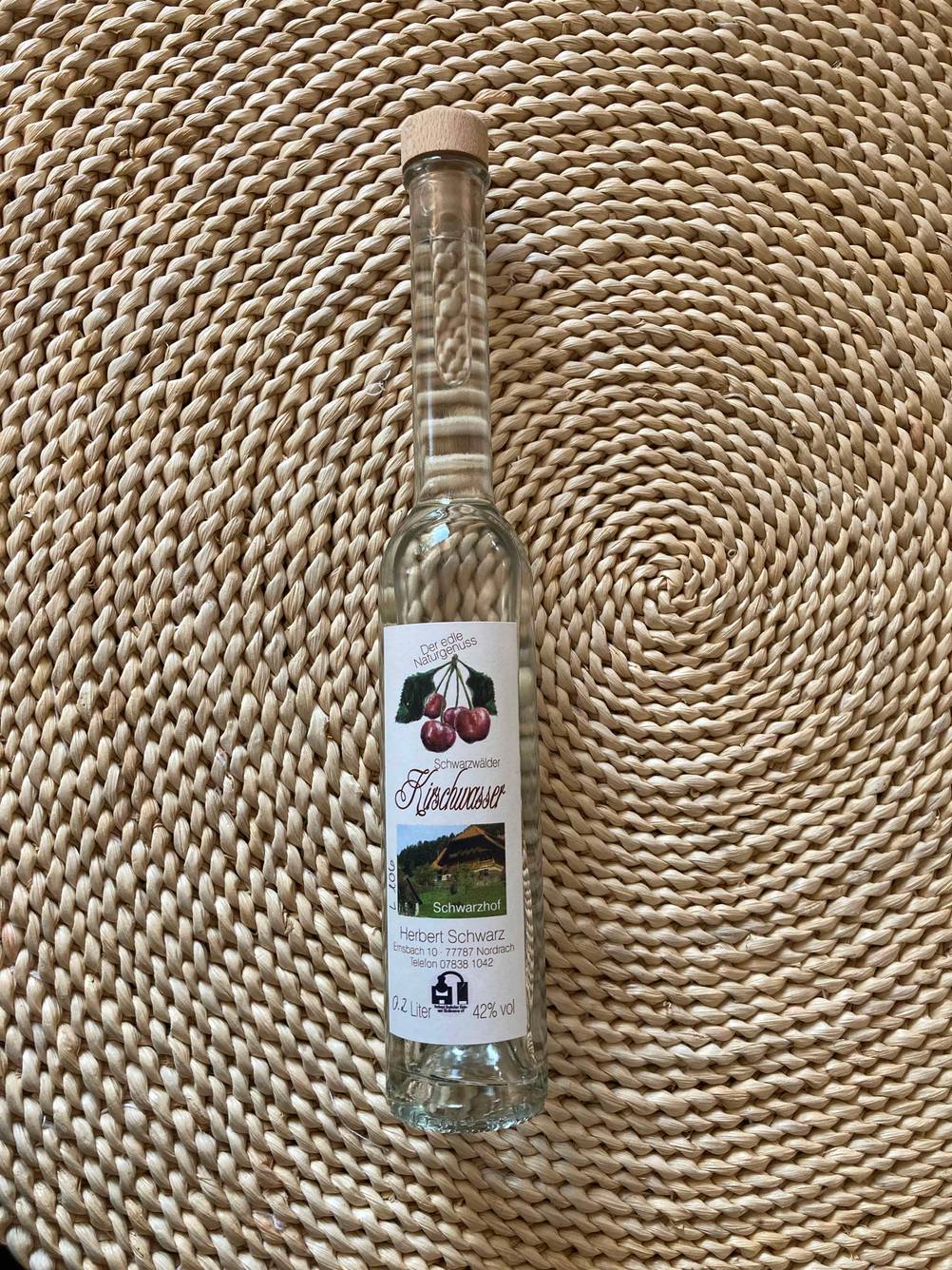 Eine Flasche Kirschwasser liegt zum Testen auf einer korkähnlichen Unterfläche.