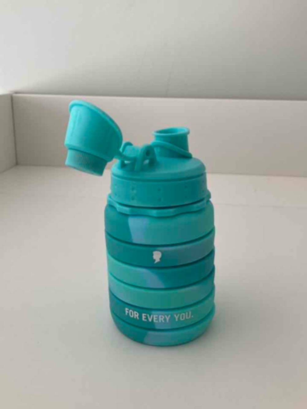 Im Test: Die faltbare Trinkflasche in Türkis steht zusammengefaltet vor einer weißen Oberfläche.