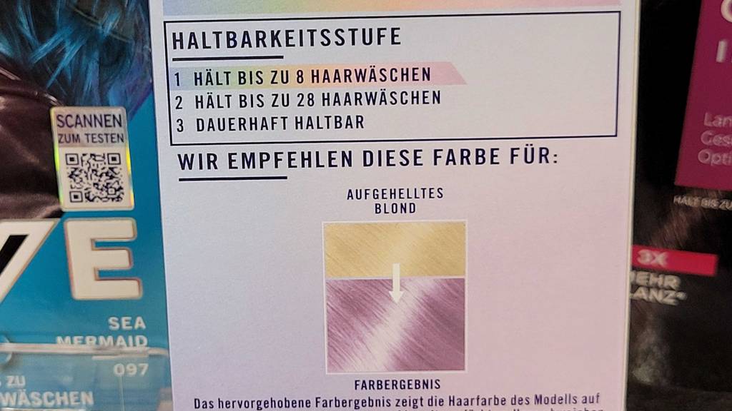 Auf der Rückseite der Verpackung von getesteter lila Haarfarbe stehen Angaben zu Haltbarkeit und Farbergebnis.