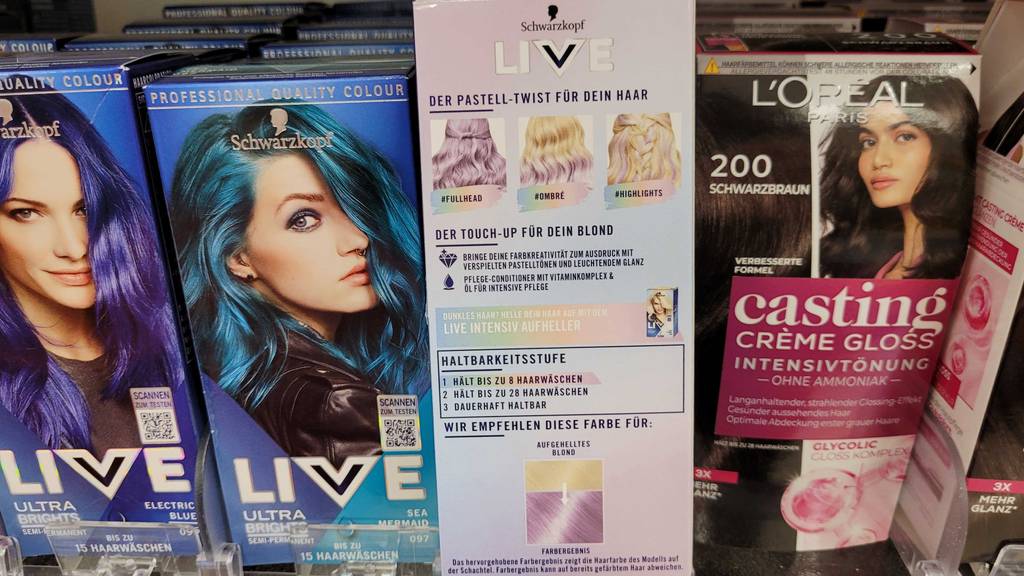 Lila Haarfarbe im Test: Eine Packung steht mit der Rückseite nach vorn in einem Regal zwischen anderen Farben.