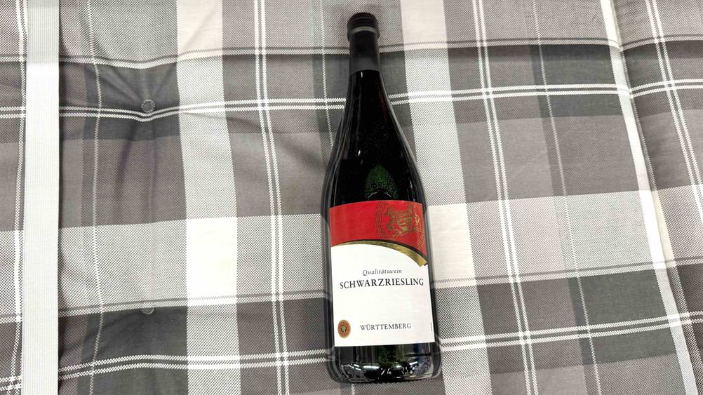 Auf einem karierten Stoff liegt eine Flasche des getesteten Schwarzrieslings.
