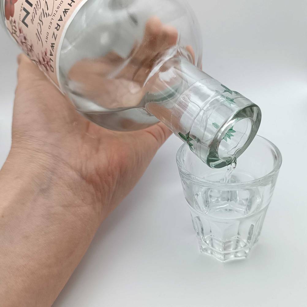 Gin wird in ein Schnapsglas gegossen.