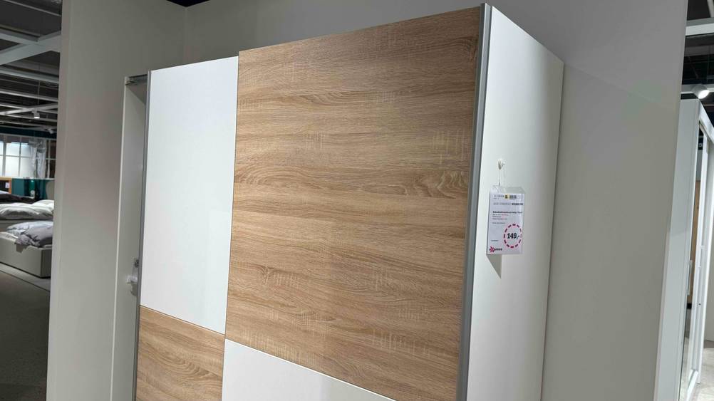 Ein getesteter Schwebetürenschrank in einer Verkaufsfläche mit Preisangaben.