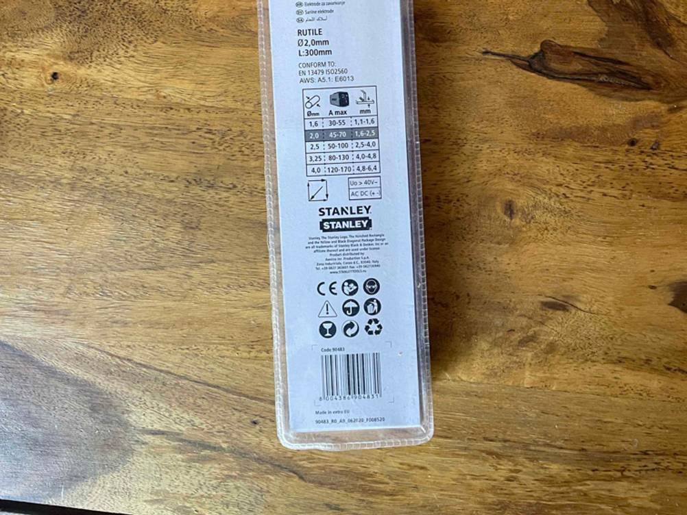 Nahaufnahme der Rückseite einer Packung der getesteten Schweißelektroden auf einem Holztisch.