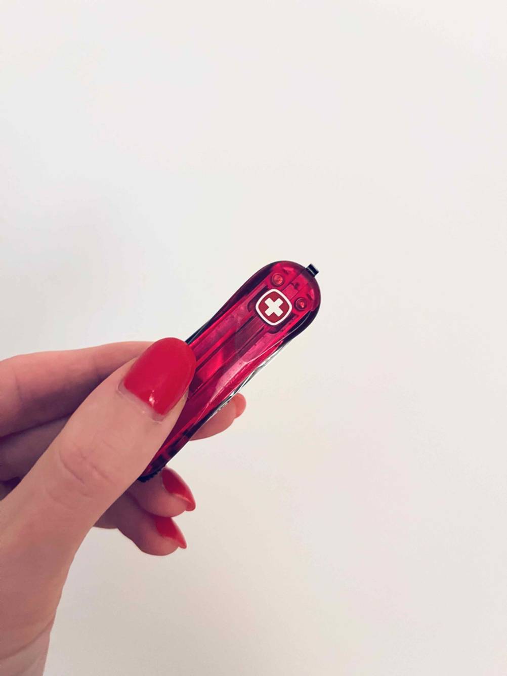 Kindertaschenmesser-Test: Eine Damenhand hält zwischen zwei Fingern ein rotes Schweizer Taschenmesser.