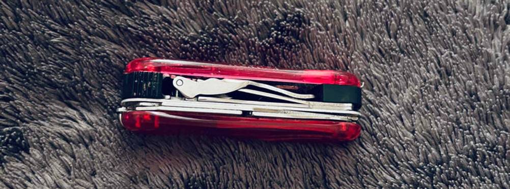 Kindertaschenmesser im Test: Seitenansicht eines roten Schweizer Taschenmessers mit verschiedenen Instrumenten.