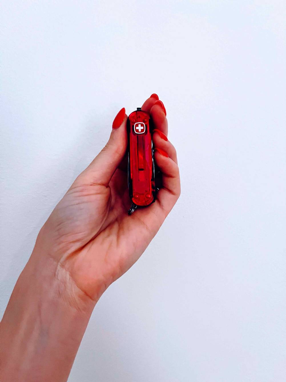 Ein getestetes Kindertaschenmesser wird von einer Hand vor einer weißen Wand gehalten.