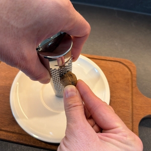 Eine Hand reibt eine Muskatnuss an der Schwertkrone-Muskatreibe