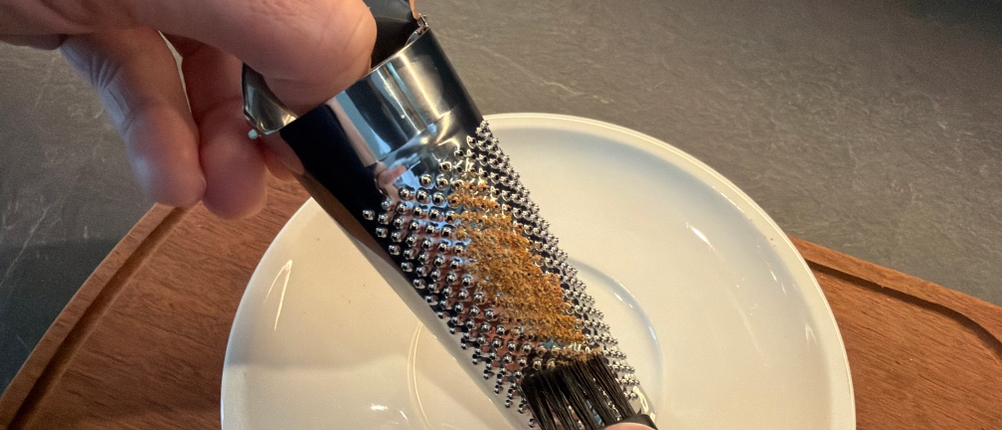 Mit einem Reinigungspinsel wird die Schwertkrone-Muskatreibe von Resten befreit