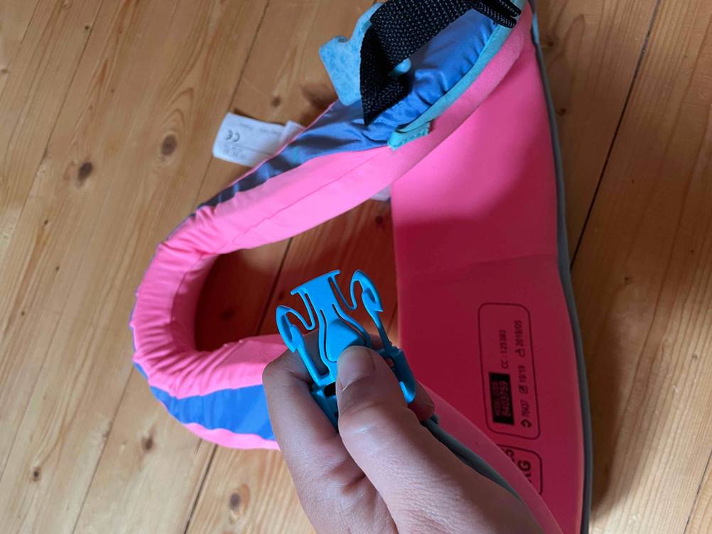 Schwimmlernweste im Test: Nahaufnahme einer Schnalle von einer Hand gehalten.