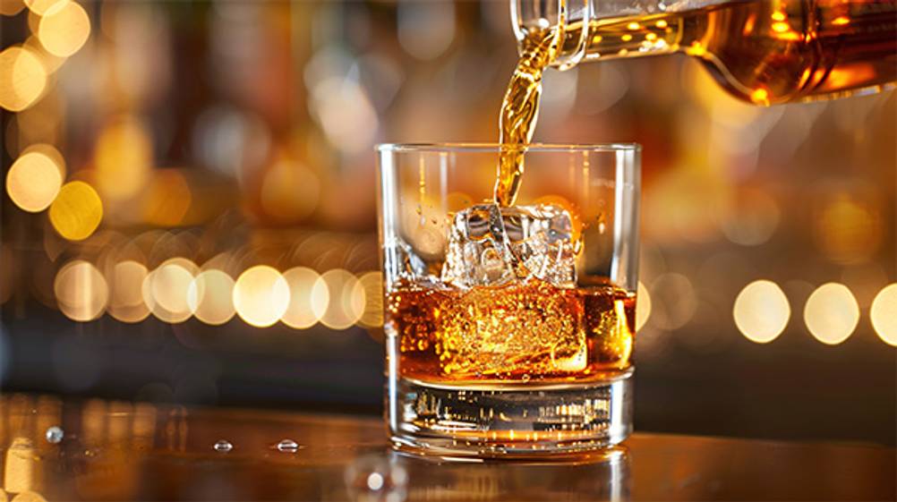Scotch im Test: Ein Barkeeper schenkt den Scotch vorsichtig in eine Glas ein. Im Glas befindet sich Eis.