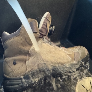 Sehr starker Wasserstrahl zielt auf einen imprägnierten Schuh in einem Waschbecken.