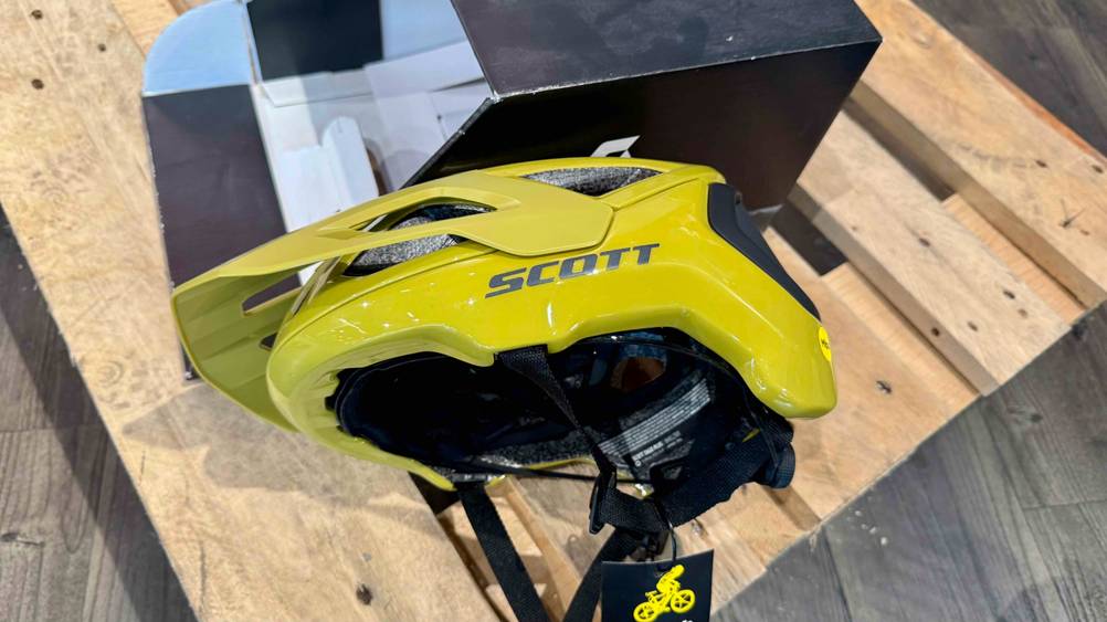 Neben der Originalverpackung liegt der Scott-Fahrradhelm im Test auf der Seite.