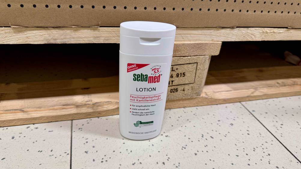 Sebamed-Bodylotion im Test: Vor einer Holzpalette steht eine Flasche auf dem Boden.