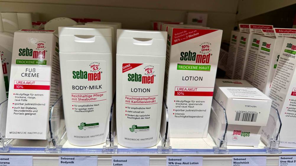 Mehrere Flaschen der Sebamed-Bodylotion im Test in einem Verkaufsregal neben anderen Produkten.
