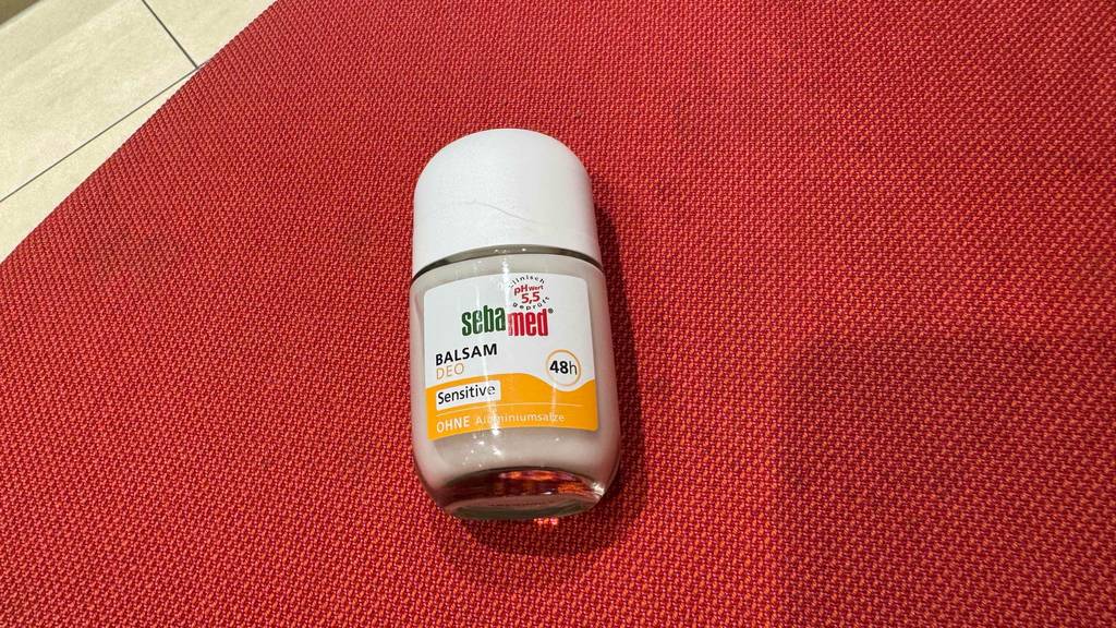 Ein Fläschchen Sebamed-Deo liegt zum Testen auf einem roten Tuch.