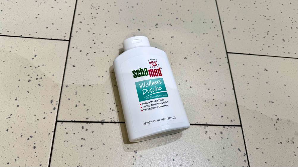 Auf einem hellen Boden liegt eine Flasche des Sebamed-Duschgels im Test.