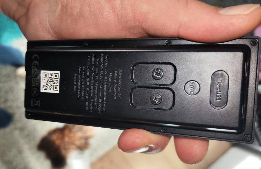 Hand hält eine getestete Video-Türsprechanlage mit ihrer schwarzen Rückseite in die Kamera.