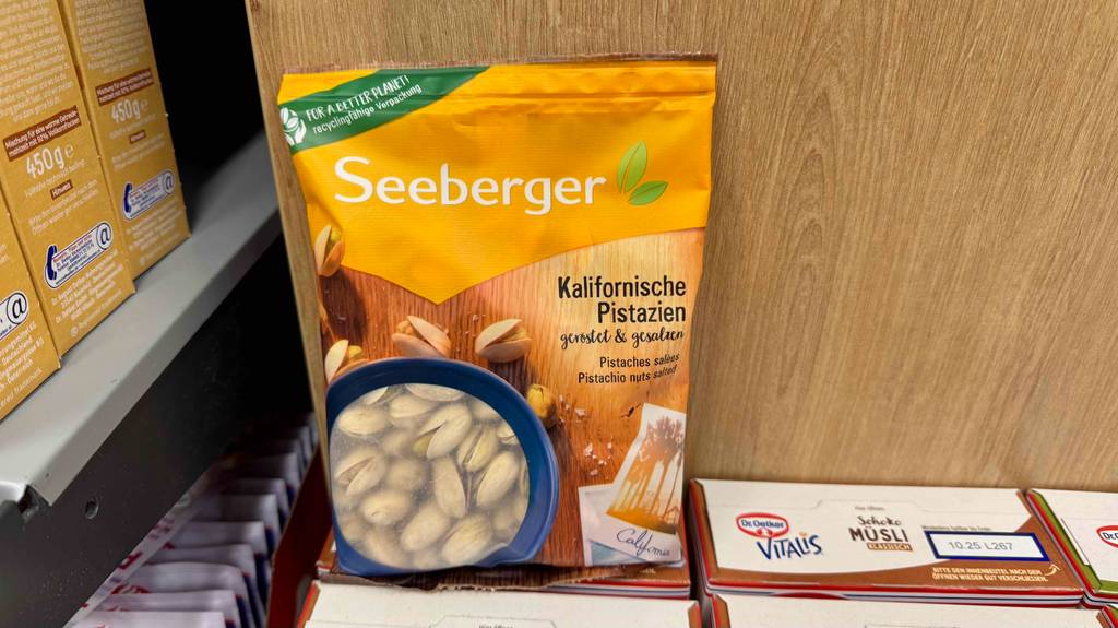 In einer wiederverschließbaren Tüte befinden sich getestete Pistazien auf einem Karton mit Vitalis-Müsli.